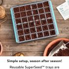 A reusable superseed™ tray filled with soil placed on a wooden table, surrounded by gardening tools and pots.